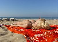 Babes: young blonde girl with a tattoo undresses her bikini on the beach towel at the sea