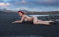 Babes: young red haired girl at the sea on the rocky shore with a black sand