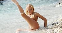 Babes: young blonde girl reveals her white fishnet knee highs in the sea on the rocky beach
