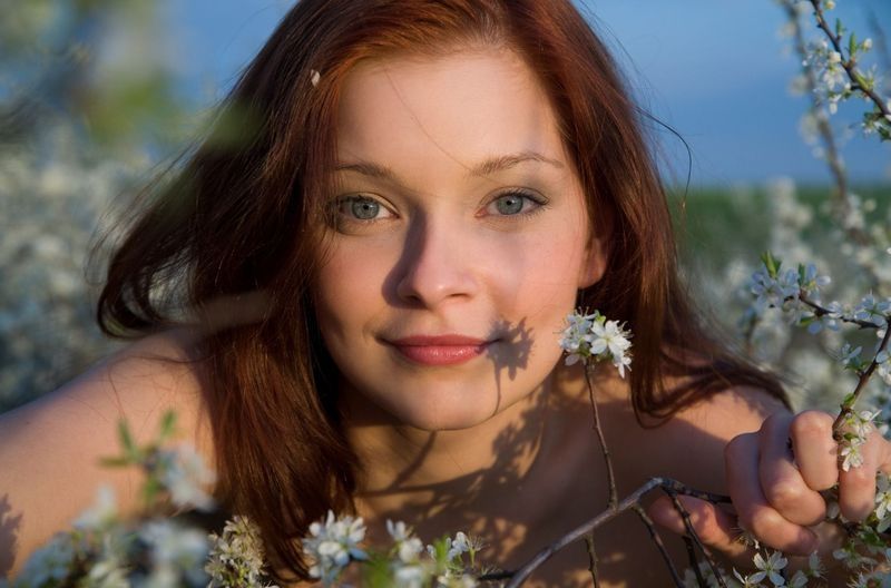 red haired girl near tree with white flowers