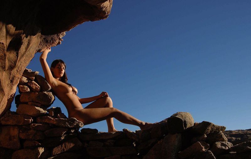 young brunette girl sunbathing on rocks