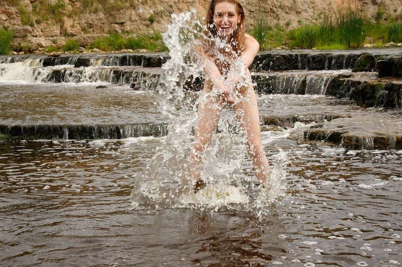 young strawberry blonde girl strips her bikini at the river