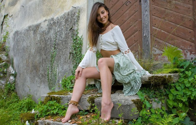 young brunette girl undresses in front of the castle's gate