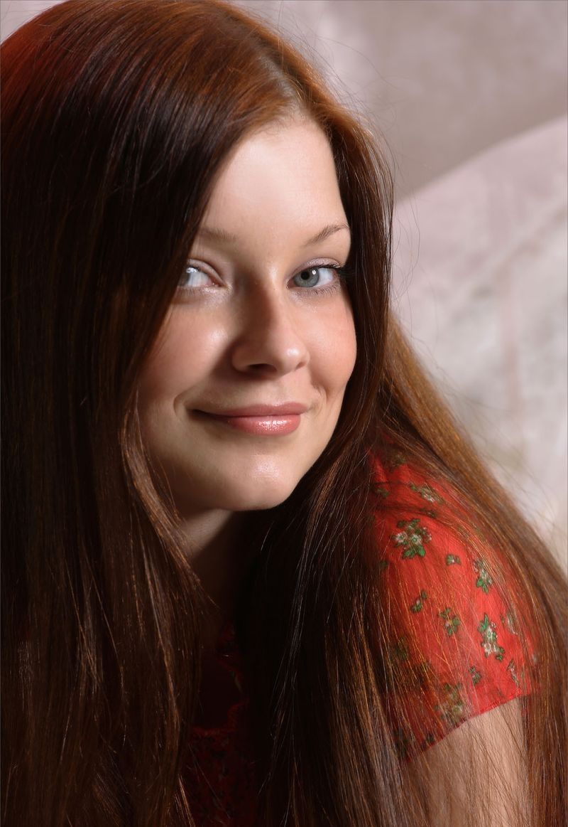 cute young brunette girl with long hair and blue eyes reveals in red clothes