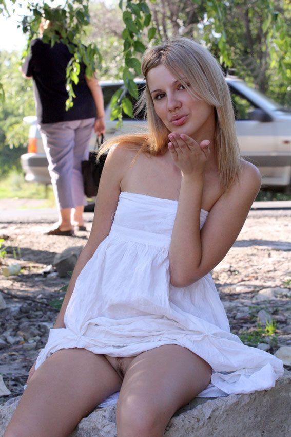 young blonde girl reveals in a white dress and black boots by the road
