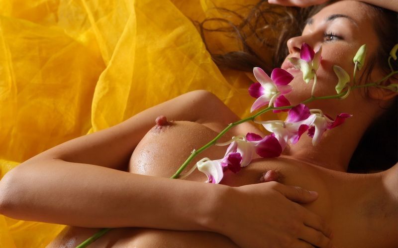 young curly brunette girl wet and poses with a flower