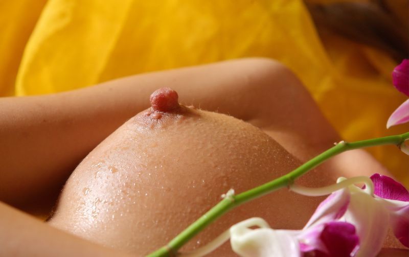 young curly brunette girl wet and poses with a flower