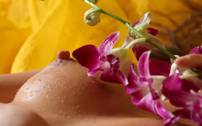 young curly brunette girl wet and poses with a flower