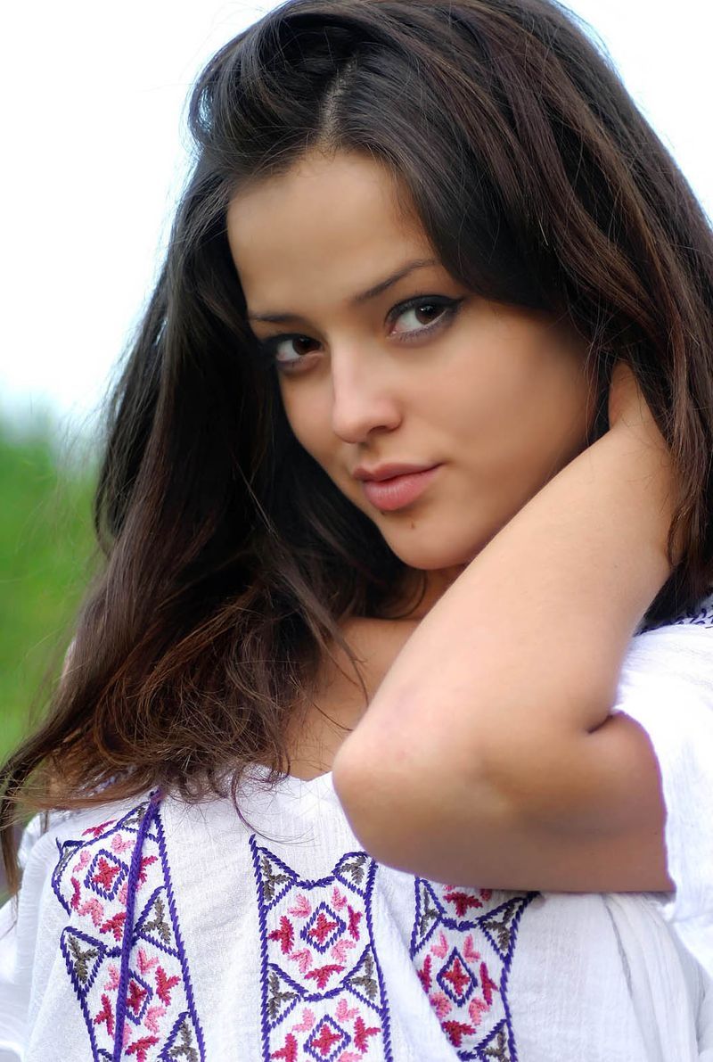 cute young brunette girl reveals on the field of wild flowers