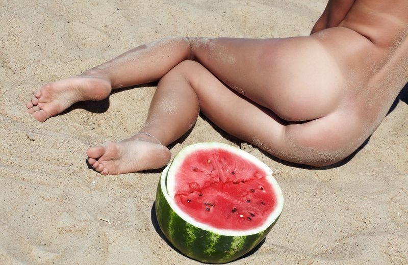 young blonde girl on the beach eating a watermelon