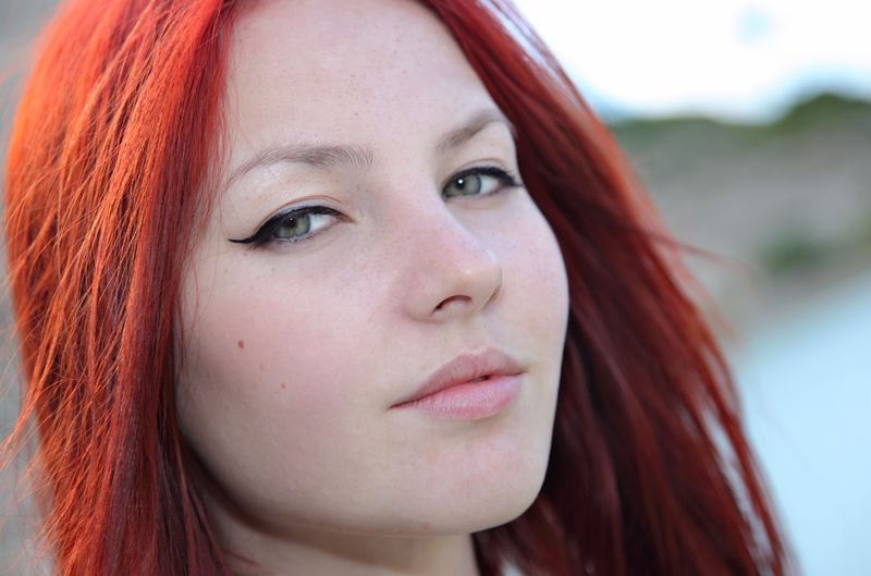 young red haired girl by the lake with blue necklace