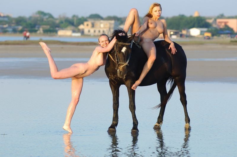 two blonde girls on the beach with a horse