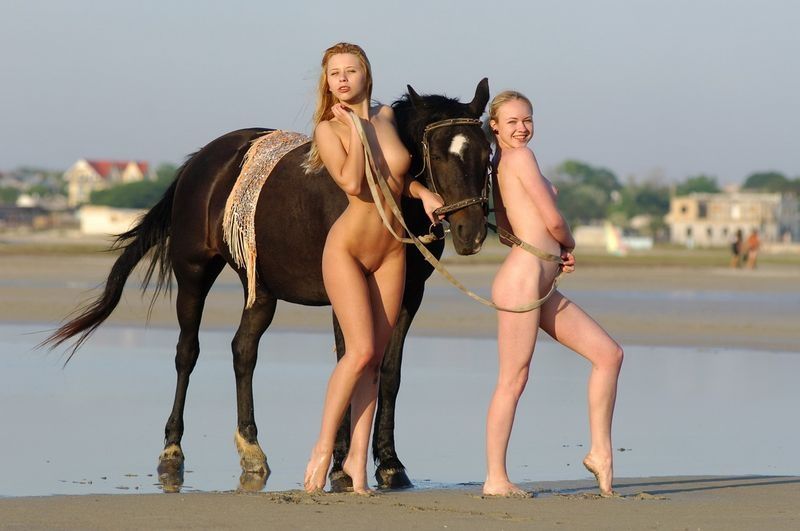 two blonde girls on the beach with a horse