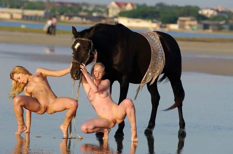 two blonde girls on the beach with a horse