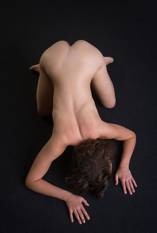 young curly brunette girl shows off on the floor in the studio