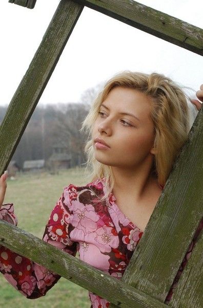 young curly blonde girl wearing a red dress in the village