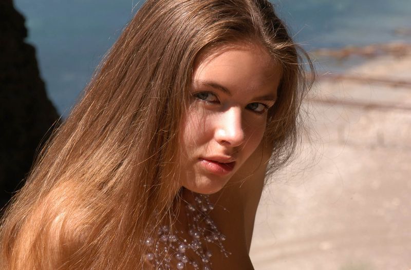 cute young brunette girl wearing a white lingerie on rocks at the sea