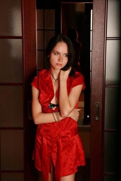 young brunette girl undresses a red dress on the couch at home