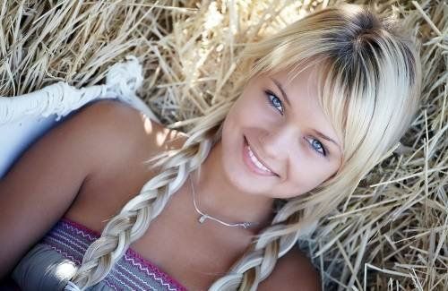 cute young blonde girl with pigtails strips in the hay