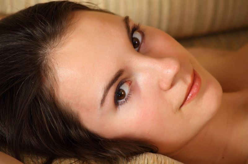 young brunette girl with a laptop strips on the couch in the living room