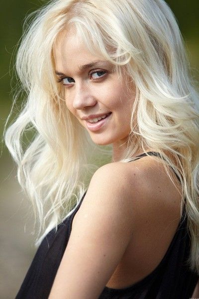 young blonde girl outside near the tree trunk