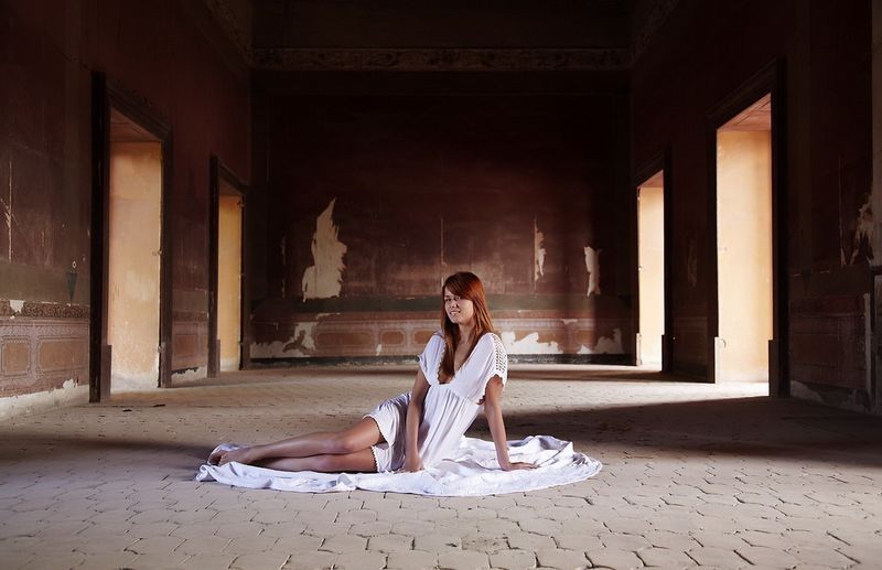 cute young red haired girl reveals her body on the floor of the large hall