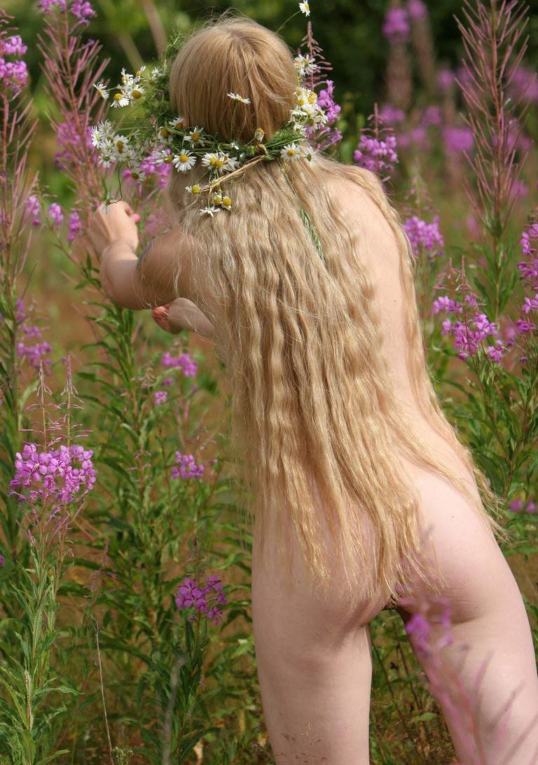young blonde girl outside making a daisy wreath