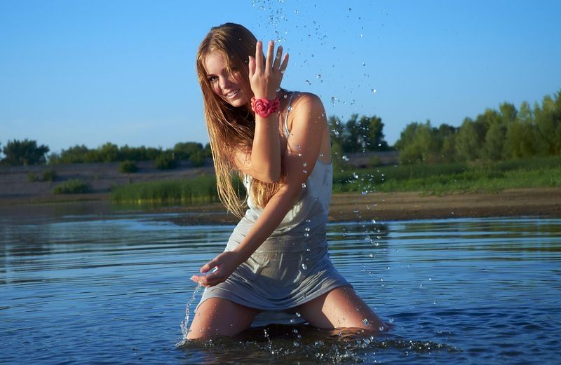 young brunette girl strips in the lake