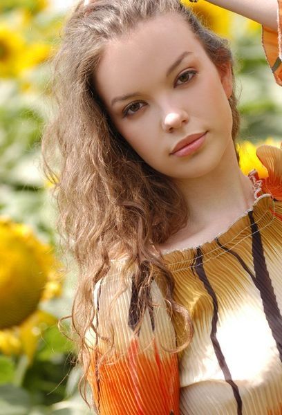 young curly brunette girl in the field of sunflowers