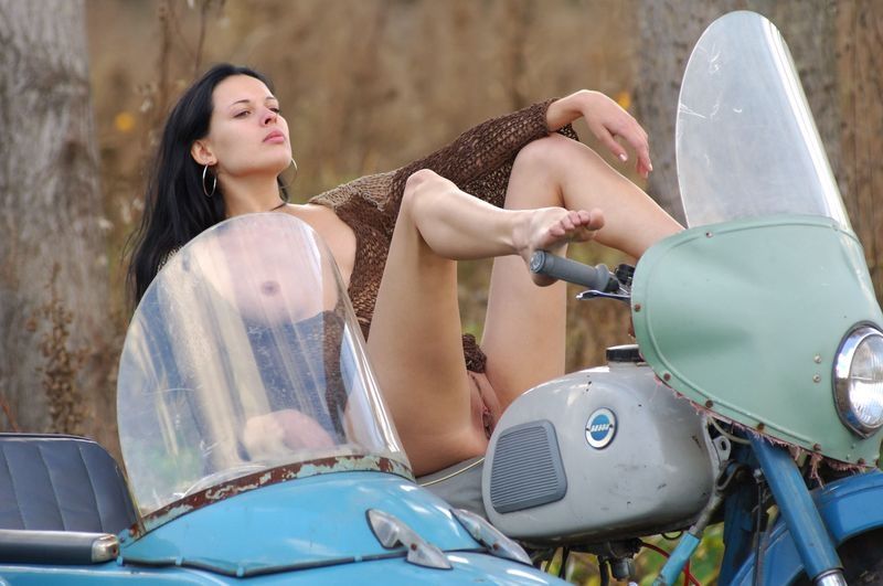 young brunette girl posing on the old sidecar