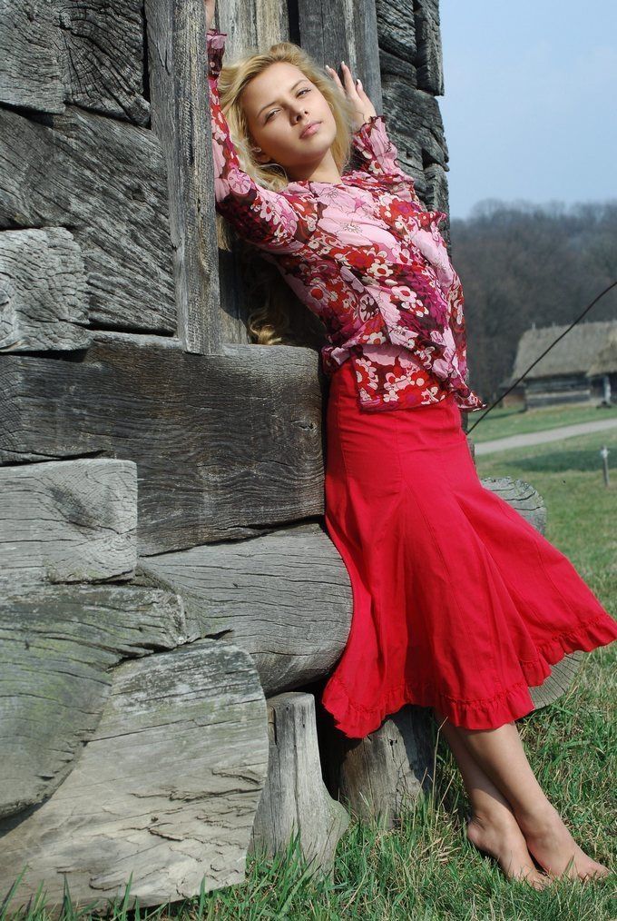 young curly blonde girl wearing a red dress in the village