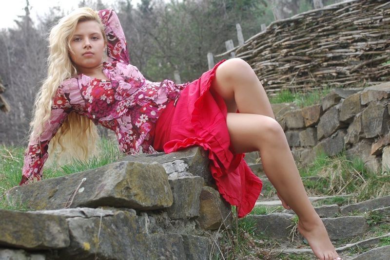 young curly blonde girl wearing a red dress in the village