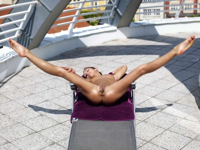 young brunette girl sunbathing on the city terrace