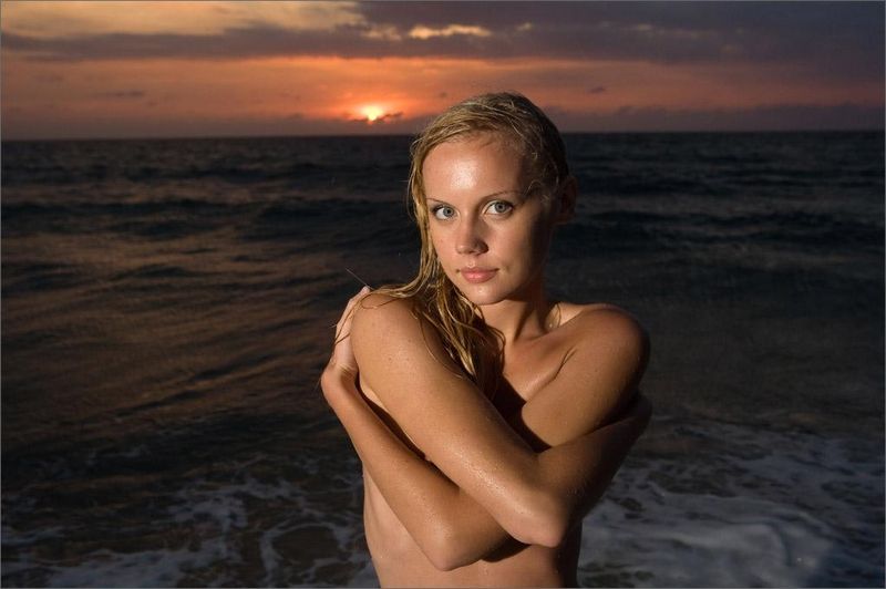 young blonde girl in the sea at sunset