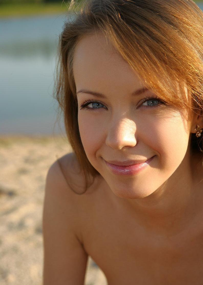 cute young brunette girl on the sand at the lake