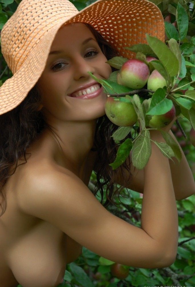 young curly brunette girl with apple trees in the garden