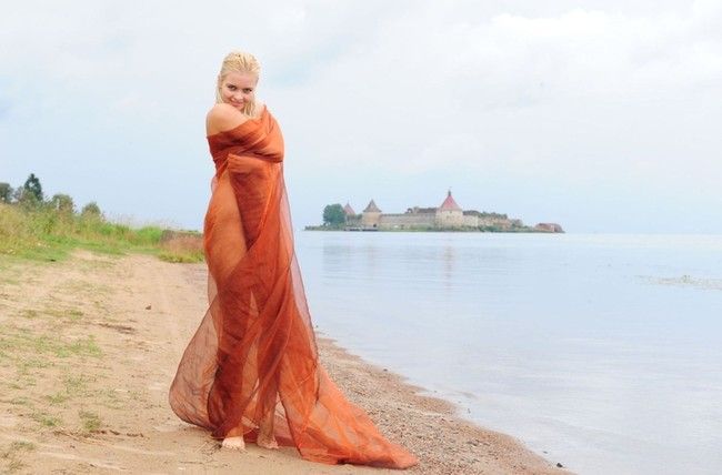 blonde girl with textile fabric at the lake with fortress