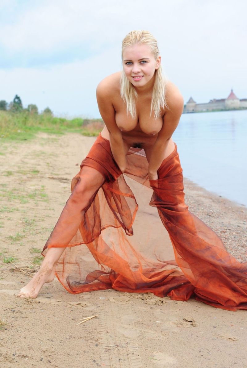 blonde girl with textile fabric at the lake with fortress