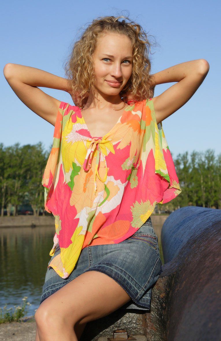 cute young curly blonde girl reveals outside on the shore