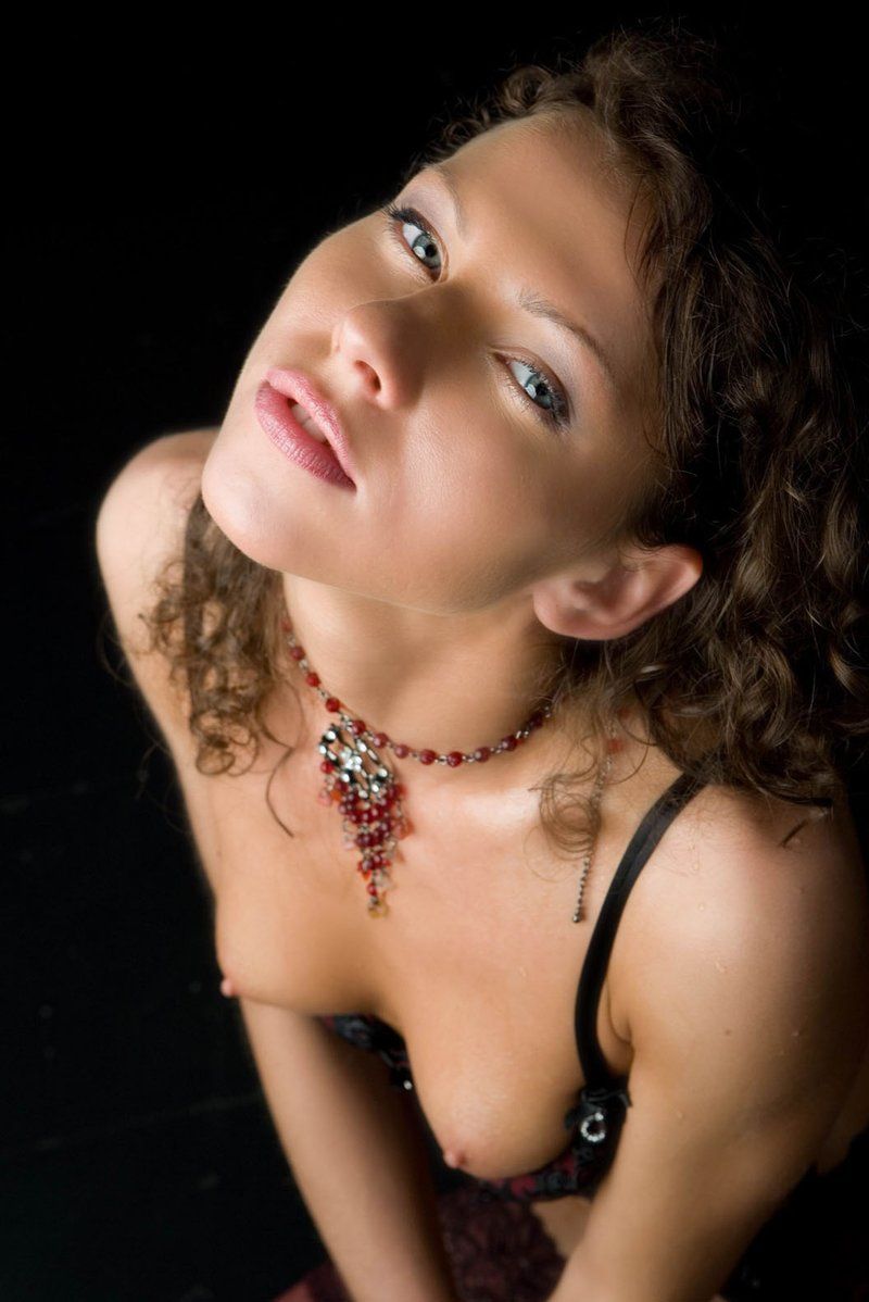 young curly brunette girl in red and black lingerie posing wet in the studio