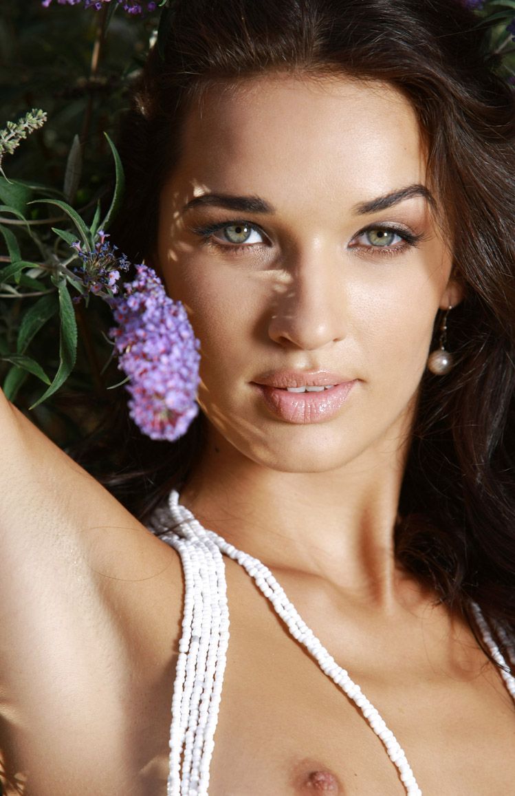 young curly brunette girl wearing necklace in the garden