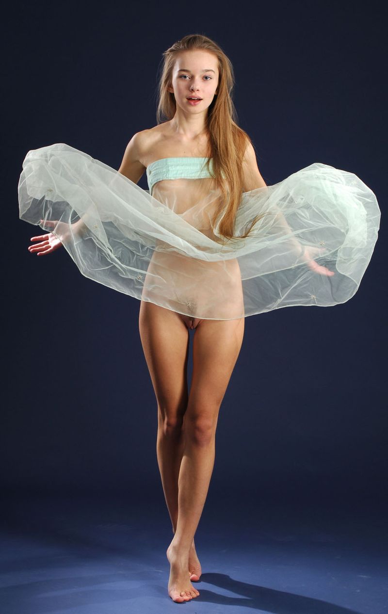 cute young blonde girl with long hair in the studio posing with a textile fabric