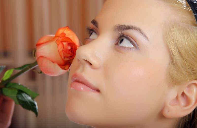 cute young blonde girl reveals on the bed with a pink rose