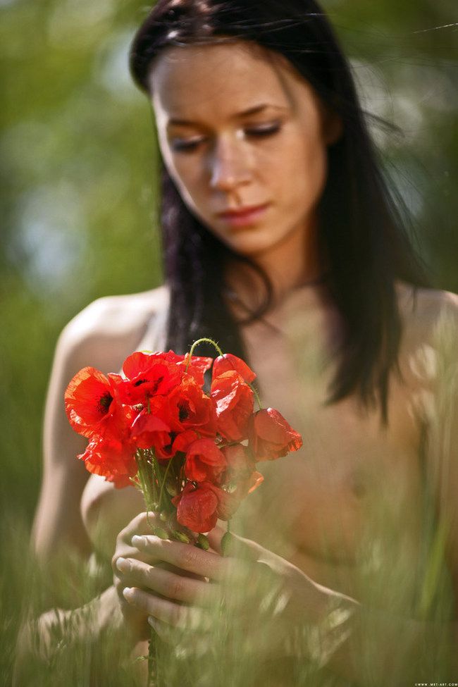 young brunette girl outside on the field with red poppies