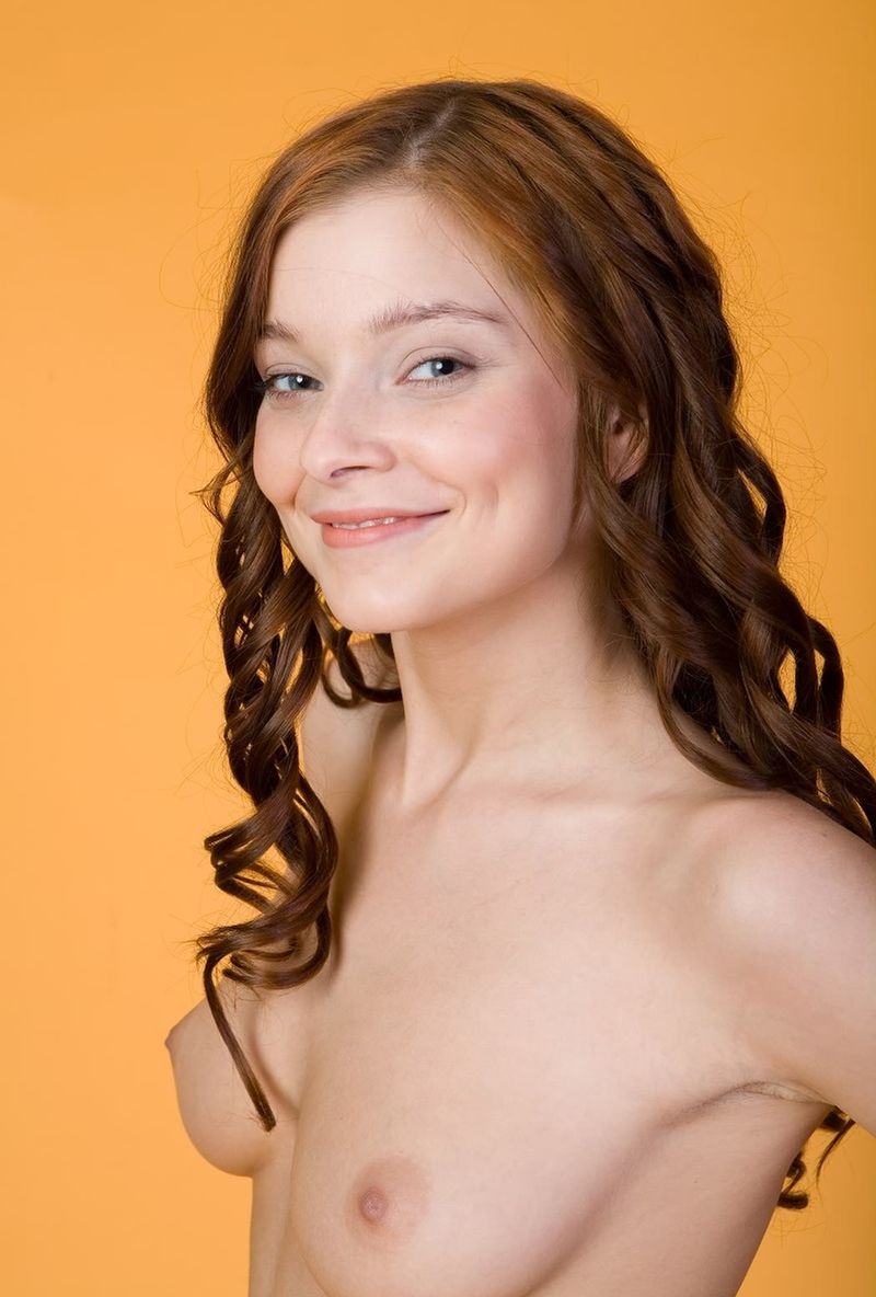 cute young curly red haired girl posing in the studio