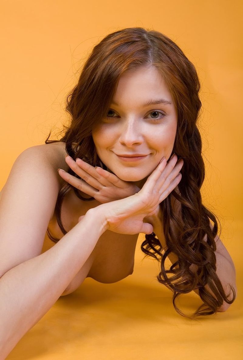 cute young curly red haired girl posing in the studio