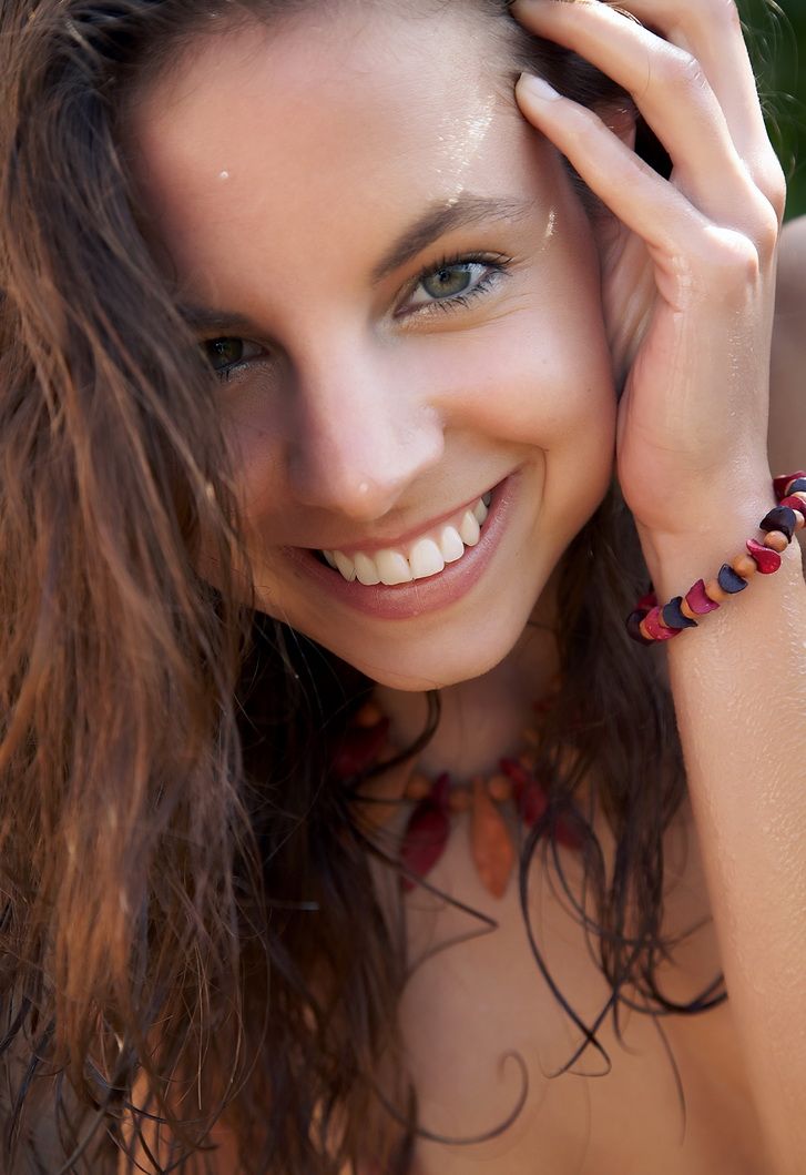 cute young brunette girl on rocks at the fence in the back garden