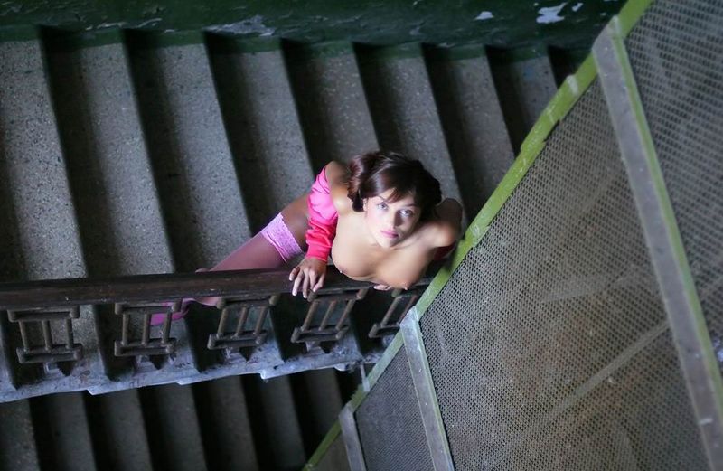 young brunette girl reveals in pink stockings and the jacket on stairs