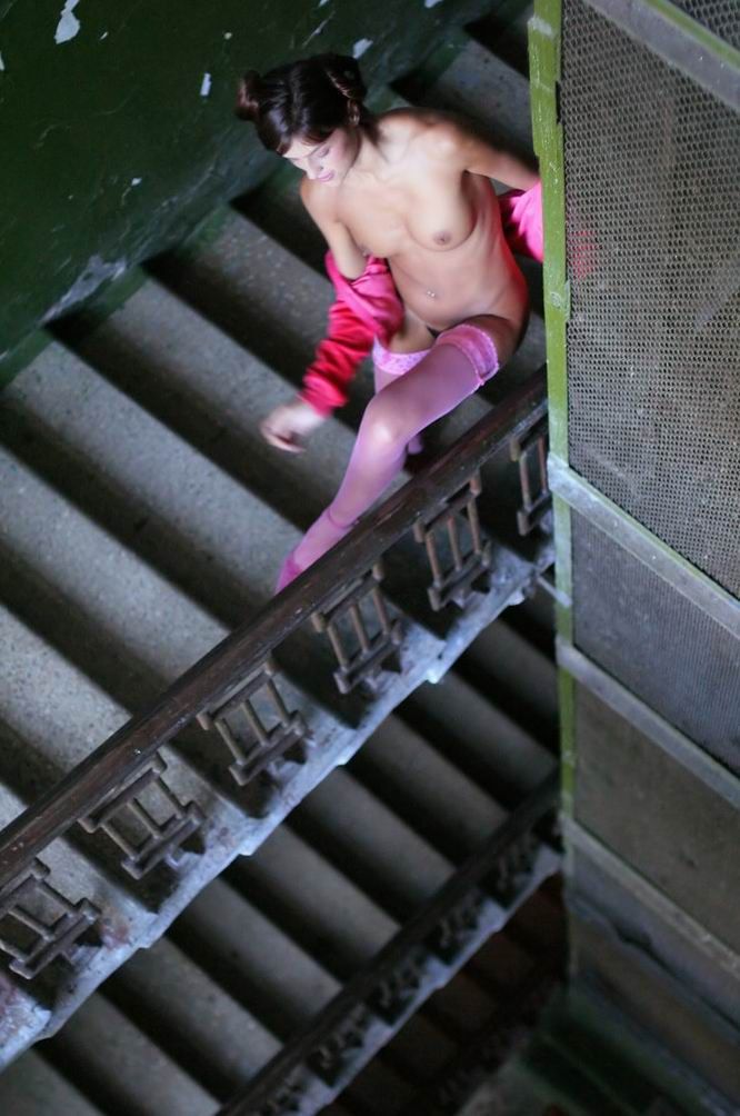young brunette girl reveals in pink stockings and the jacket on stairs