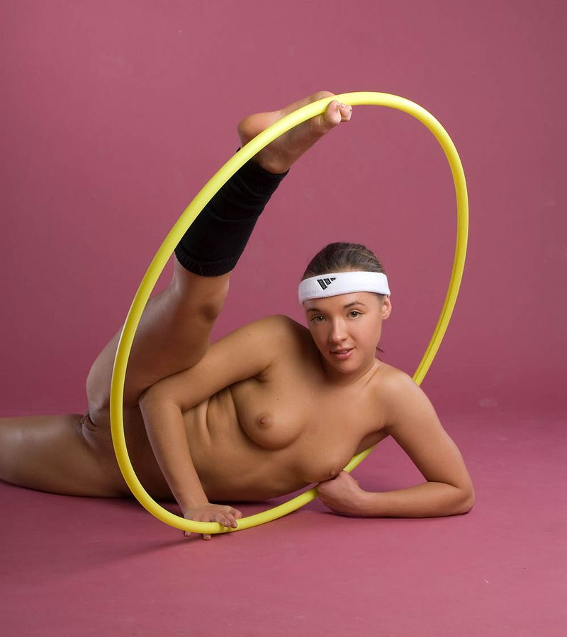 cute young brunette girl with a white headband doing flexible exercises with the gymnastic hoop